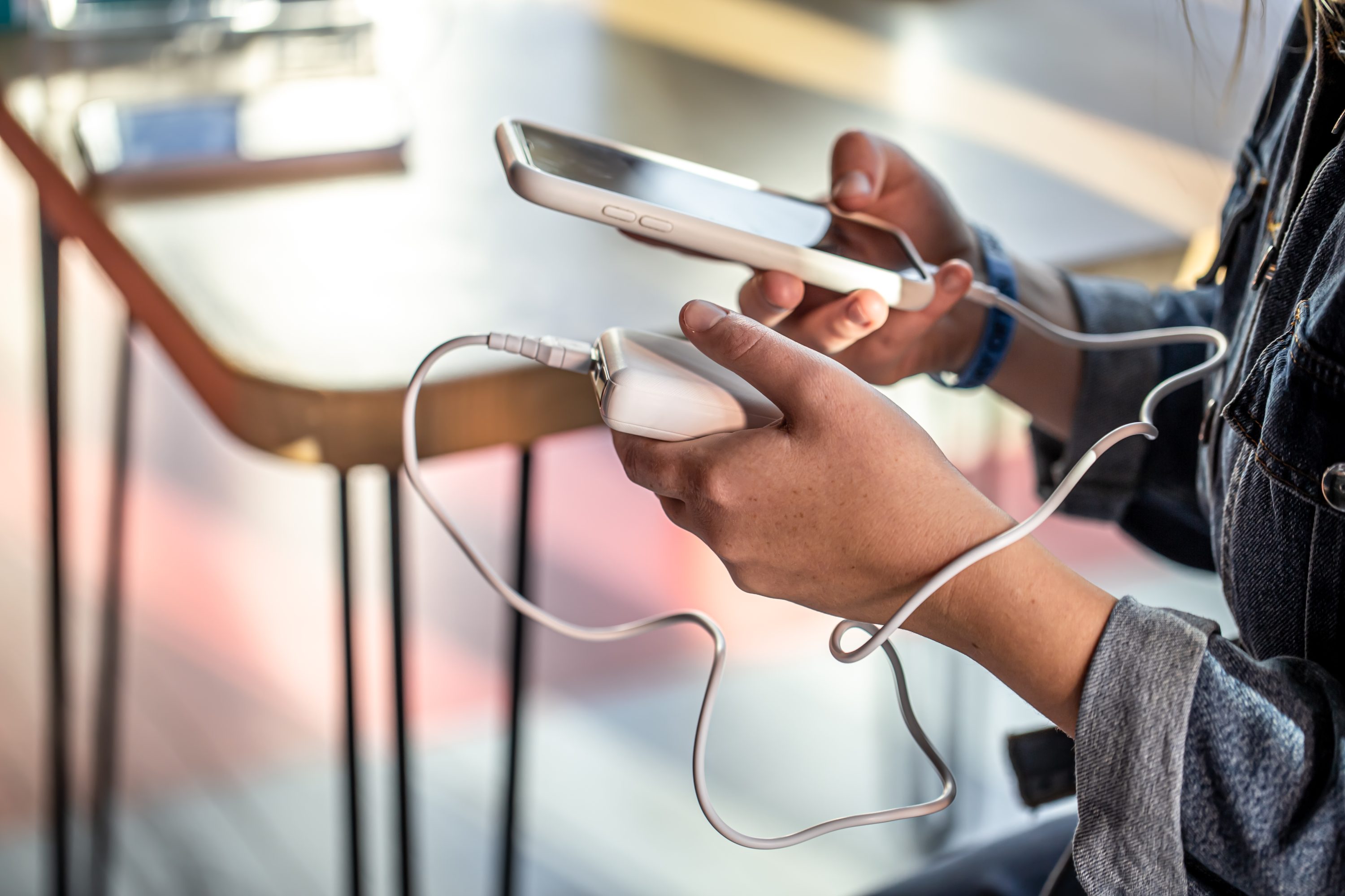 A woman holds a power bank and a phone in her hands.