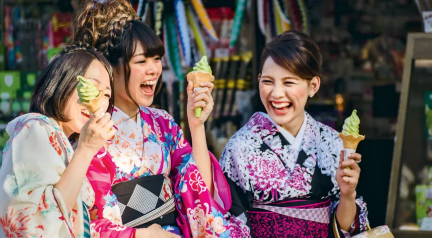 три девушки смеются и едят мороженое