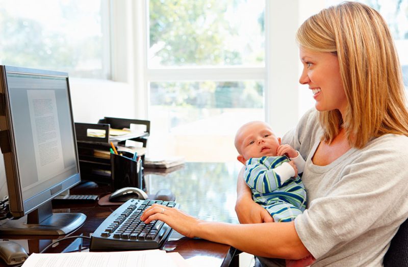 Девушка работает с младенцем на руках