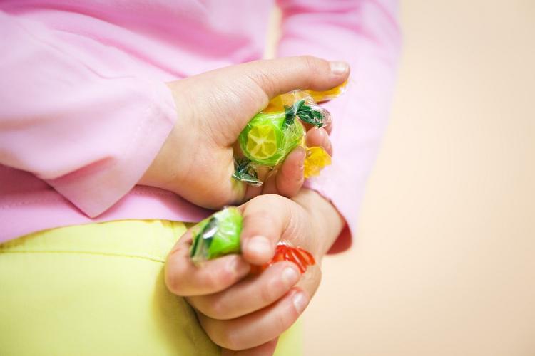 ребенок прячет конфеты 