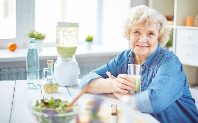 Пожилая женщина пьет смузи