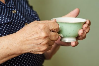 Пенсионерка держит чашку чая в руках лечебный чай